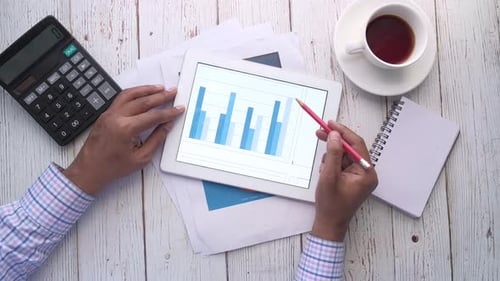 Man's Hand Working on Digital Tablet at Office Desk, Using Self Created Chart