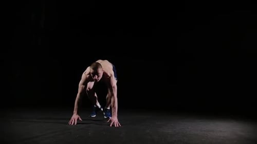 A Young Sports Man Doing a Backflip and Doing a Push Up Endirance Training in Black Studio