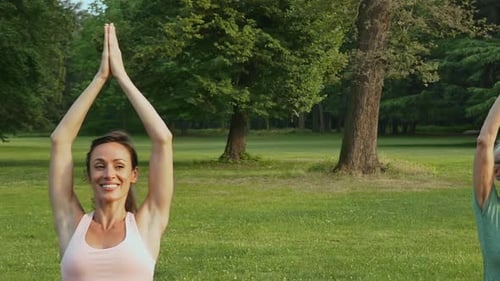 Women Practicing Yoga Outdoors on Green Grass