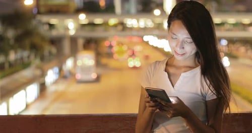 Woman using smart phone in the city at night
