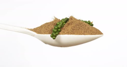 Fresh green pepper, piper nigrum, spice falling in pepper ground on white background, slow motion 4K