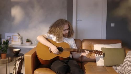 Man Playing Guitar Relaxing on Couch at Home