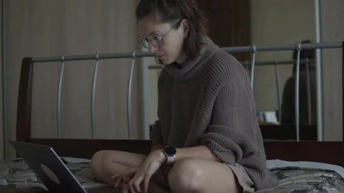 Woman Working on Laptop Sitting on Bed