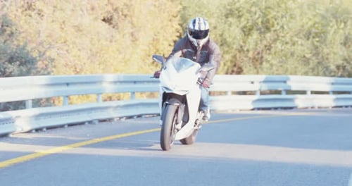 Man riding on a white sports motorcycle in a curvy highway