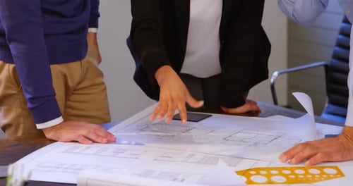 Team Collaborates on Building Plans in Office