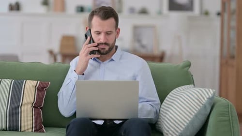 Man Talking on Phone while Using Laptop