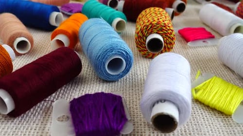 A top view of colorful mouline threads and multicolored spools isolated on a burlap background.