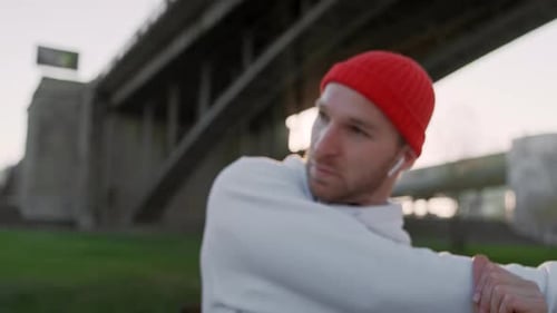 Young Man Stretching His Arm Muscles Under the Bridge Before Running. Handsome Athlete Male Doing
