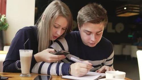 Young Man Writing a Letter or Doing His Homework in a Cafe