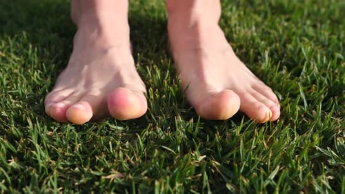 Frauenfüße auf Gras. Lindert Schmerzen. Gesundheitliche Konzepte