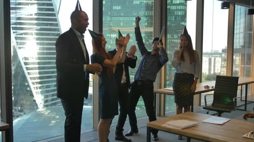 Colegas felizes comemorando aniversário no moderno escritório de coworking. Serpentina, tubos.