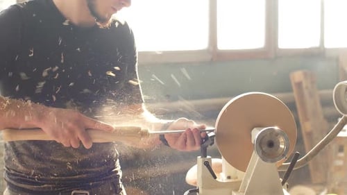 Attractive Carpenter Working on Woodworking Lathe Machine in The Carpenter Workshop.