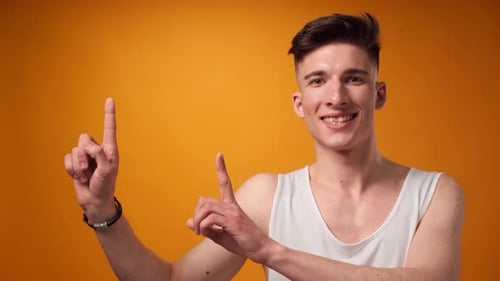 Smiling Man Points Upward on Orange Background
