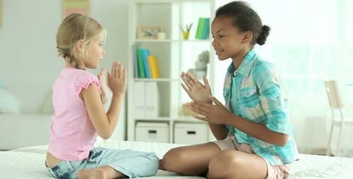 Cheerful Girls Play Clapping Game on White Bed