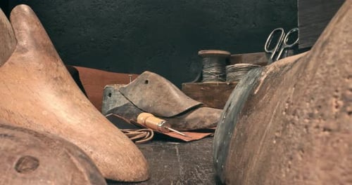 Petit lieu de travail de cordonnier avec outils, sangle, cuir et règles.