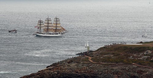 Large Sailboat Sailing Near a Rocky Coastline