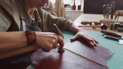 Woman Smoothing Leather Edges in Workshop