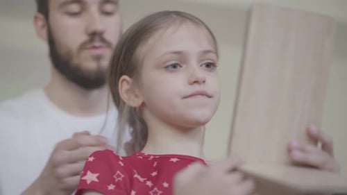 Father Puts Toy Crown on Young Daughter at Home