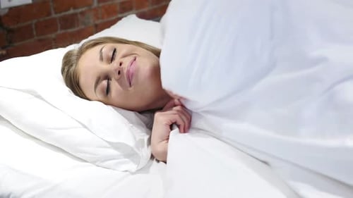 Happy Woman Sleeping Peacefully in White Bed