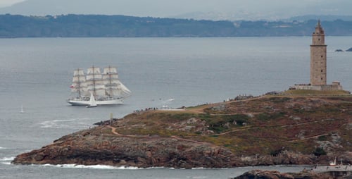 Scenic Tall Ship Sailing near Coastal Island Tower
