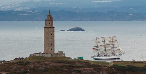 Sailing Ship Passing Ancient Coastal Lighthouse