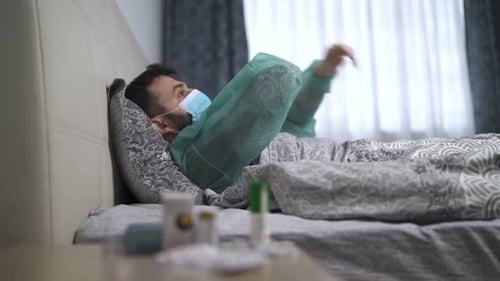 Man Resting in Bed Wearing Surgical Mask