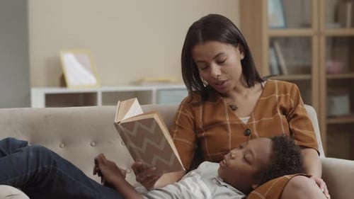 Mother Reading Book to Child on Couch