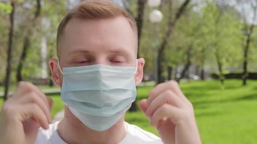 Man Putting on Face Mask Outdoors in Summer