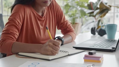 Asian creative woman write idea planning big project to notebook during work from home.