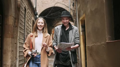 Couple Walks Through European City Street Looking at Map