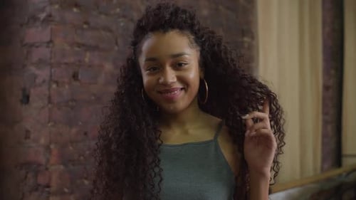 Woman Smiling and Posing in Front of Brick Wall