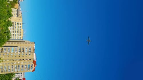 Plane Flies Over City on Sunny Day