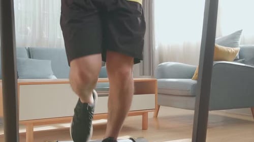 Front View Of Asian Man Running On A Treadmill At Home