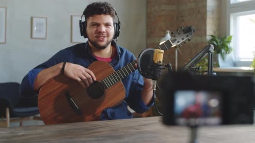 Male Musician Filming Guitar Vlog with Camera in Recording Studio