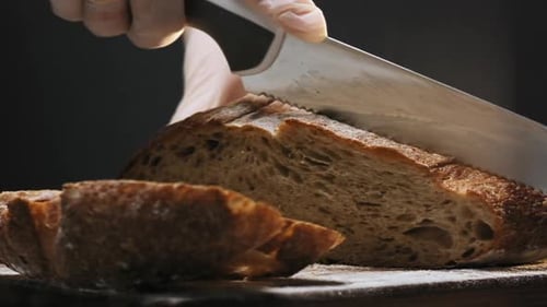 Gloved Hand Slices Fresh Bread with Knife