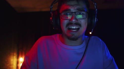 Male gamer playing games on computer and grimacing with irritation, front view. Male nerd gamer play