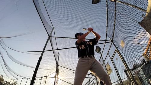 Baseball Player Practicing Hitting in Batting Cage
