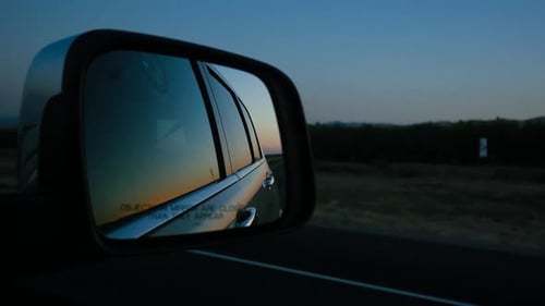 Car Side Mirror Reflecting Sunset Landscape While Driving