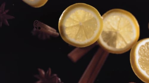 Lemon Slices and Cinnamon Floating Against Black Background