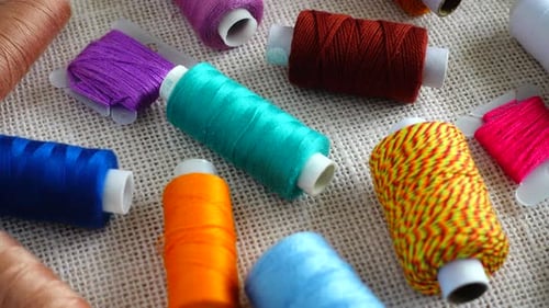 A top view of colorful mouline threads and multicolored spools isolated on a burlap background.
