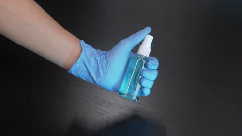 Gloved Hand Holding a Blue Spray Bottle