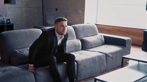 Man in Suit Relaxes on Modern Couch