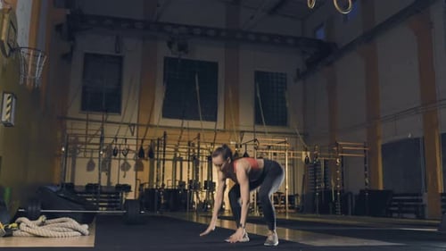 Jeune femme faisant du burpee dans une salle de sport