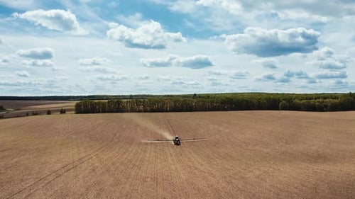 Tractor sprays on field. Aerial view of agricultural sprayer tractor