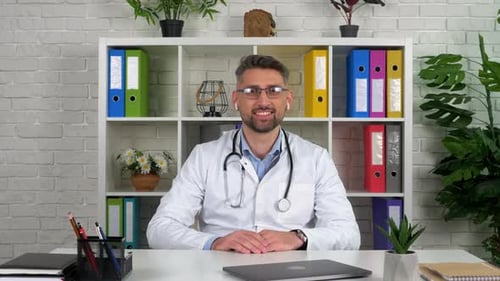 Friendly Doctor at Desk Wearing Stethoscope and Earbuds