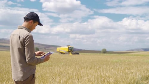 The farmer is in the field with his tablet in hand.