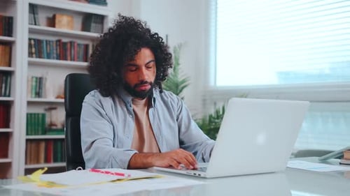 Jeune programmeur arabo-américain tapant sur le clavier frustré