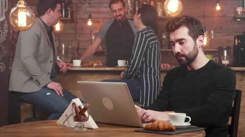 Hübscher Mann beendet das Tippen an seinem Laptop und verlässt den Tisch