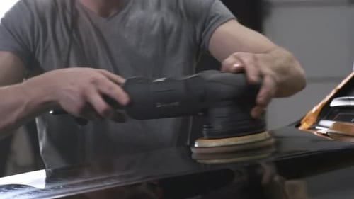 Man Buffing Paint on Black Car with Machine