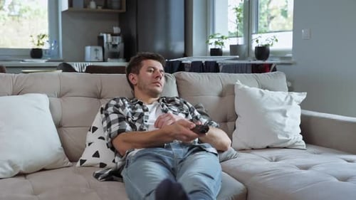 Man Relaxes on Couch with Remote Control
